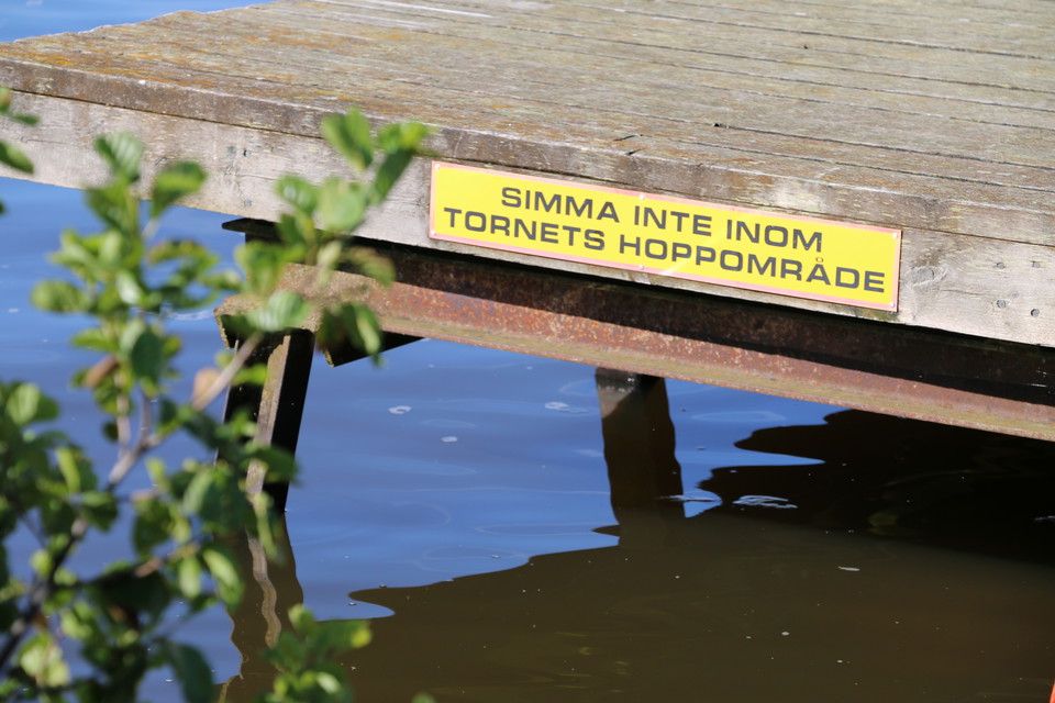 Skylt på bryggan med en uppmaning om att inte simma inom tornets hoppområde.