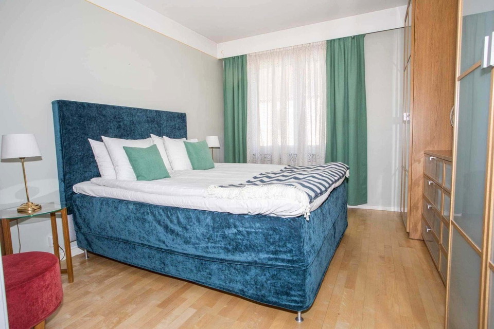 En säng med kuddar och en blå sänggavel i ett rum.