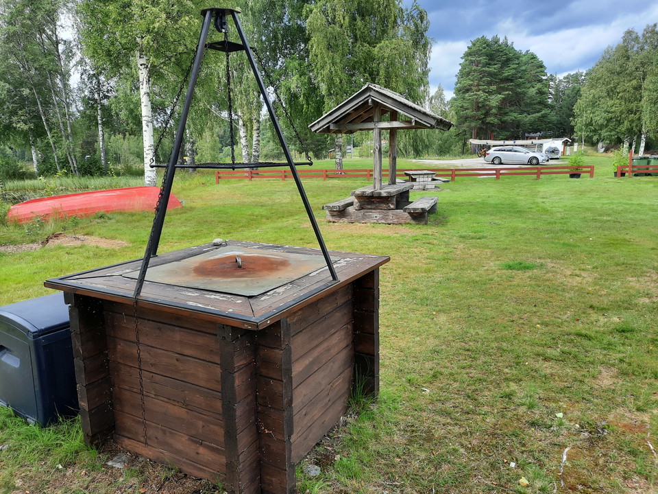 Grillplats. I bakgrunden syns parkering och ställplats för husbil/husvagn