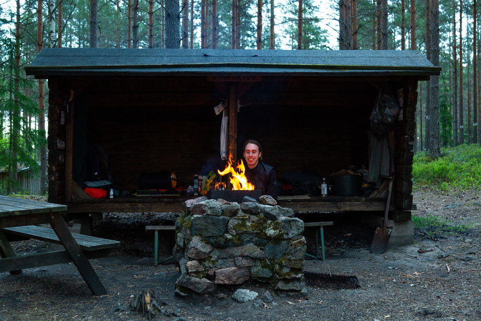 Person som eldar vid en eldstad och vid ett vindskydd