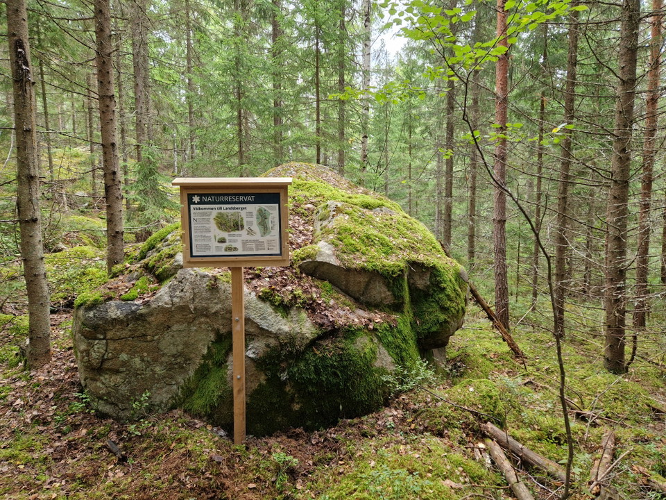 Informationsskylt om naturreservatet står bredvid sten.