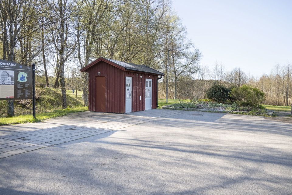 Rött servicehus vid asfalterad parkering.