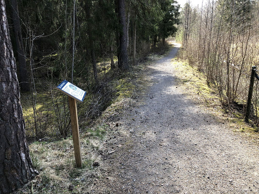 Informationstavla vid grusad stig.