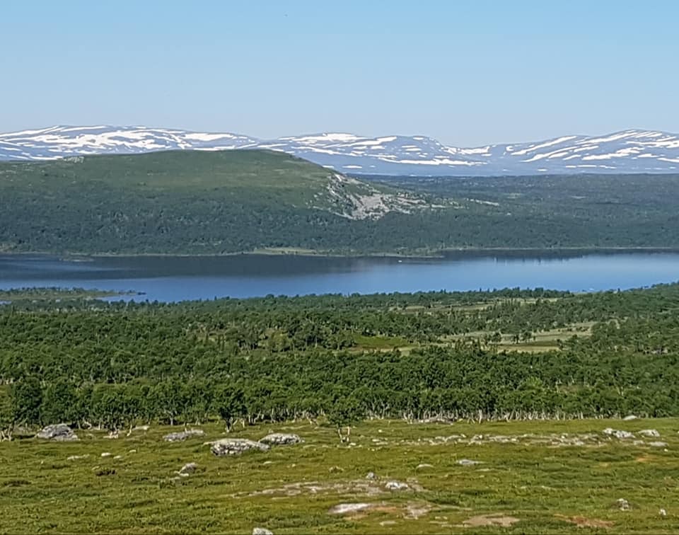 Översiktsvy med Glensjön och delvis snöklädda fjäll i bakgrunden