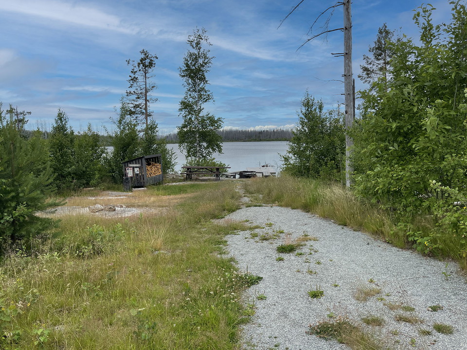 Bred grusad stig mot grillplats vid vatten.