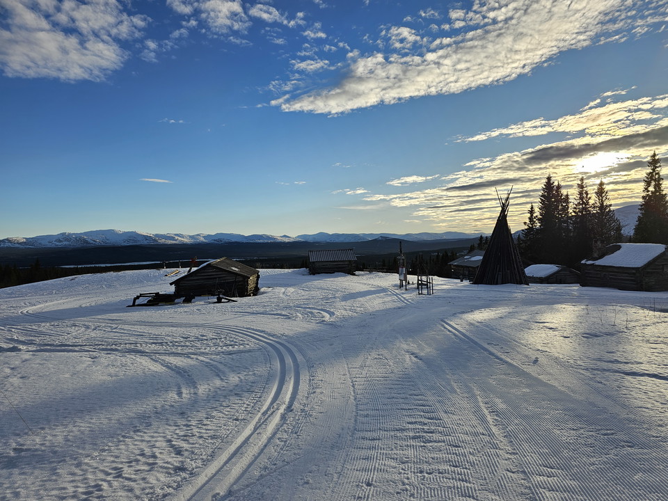 Skidspår som leder fram runt en låg fäbod.