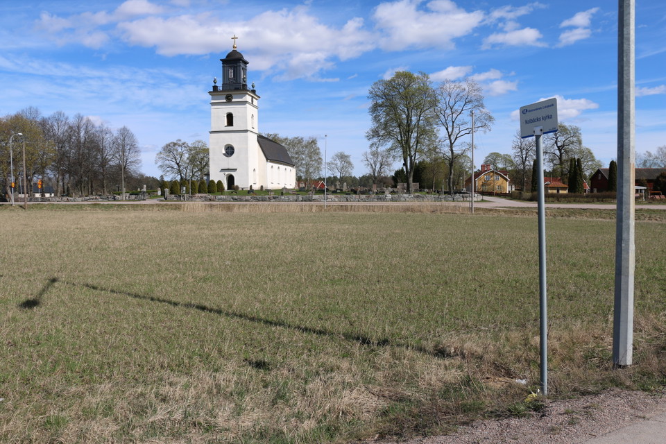 Busshållplatsskylt med kyrkan i bakgrunden.