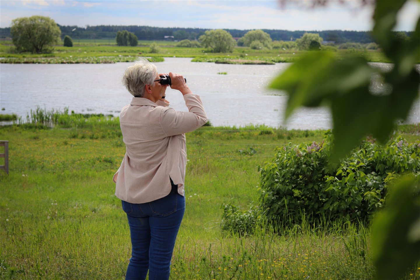 En kvinna tittar med kikare ut över en sjö