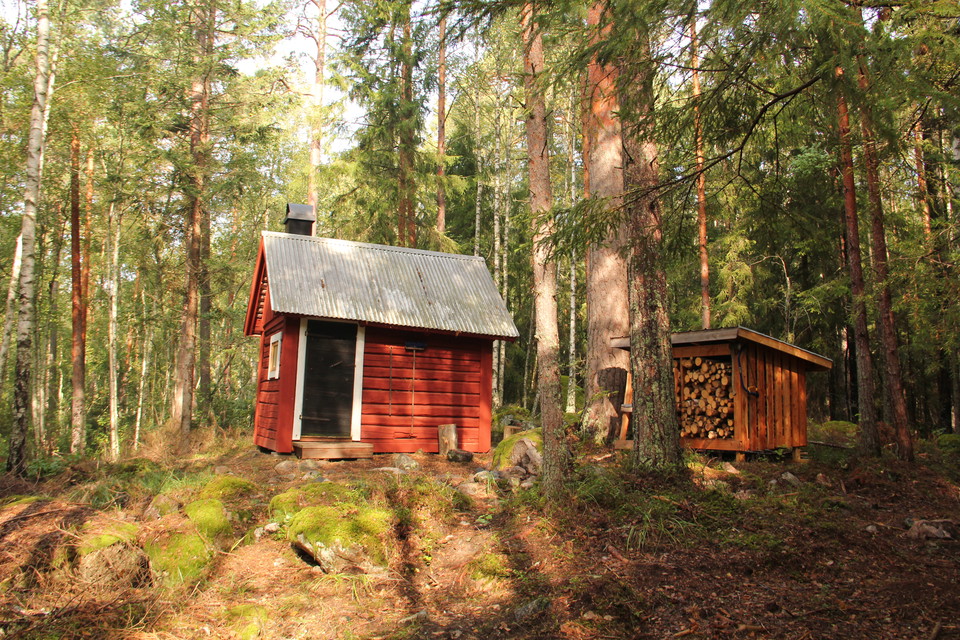 Liten röd stuga med vedförråd.