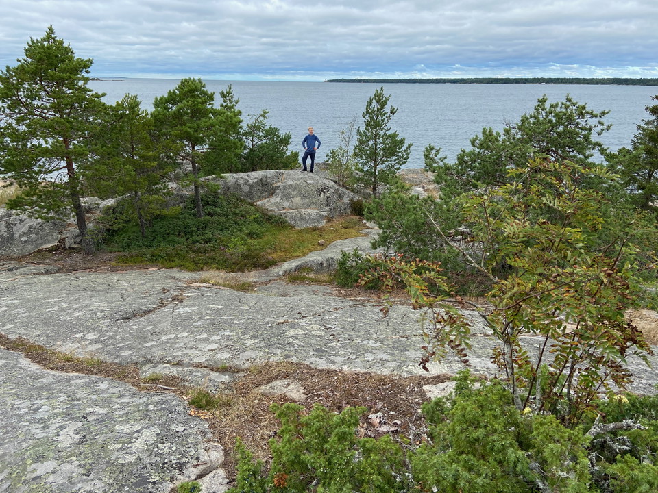 En pojke står långt bort på en klippa. I bakgrunden syns havet.