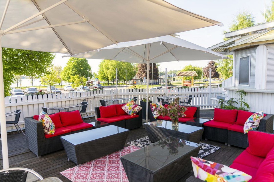 En uteplats med vitt parasoll och röda möbler.