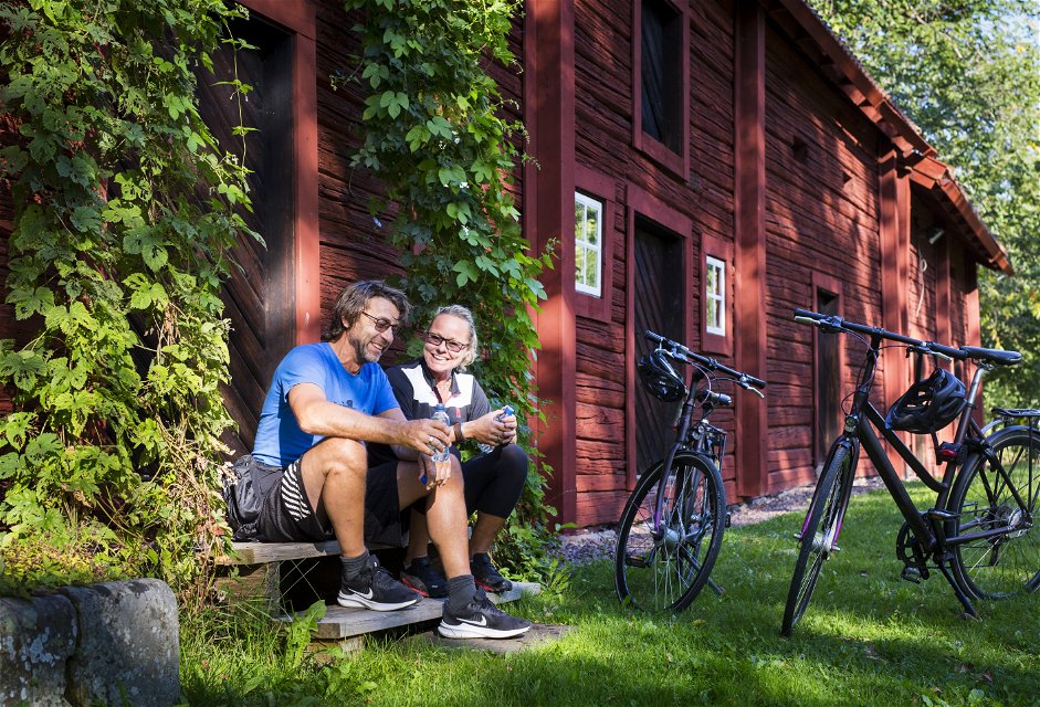 Två personer vilar utanför röd byggnad i Borgvik