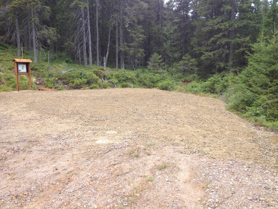 Grusparkering med reservatsskylt och skog i bakgrunden