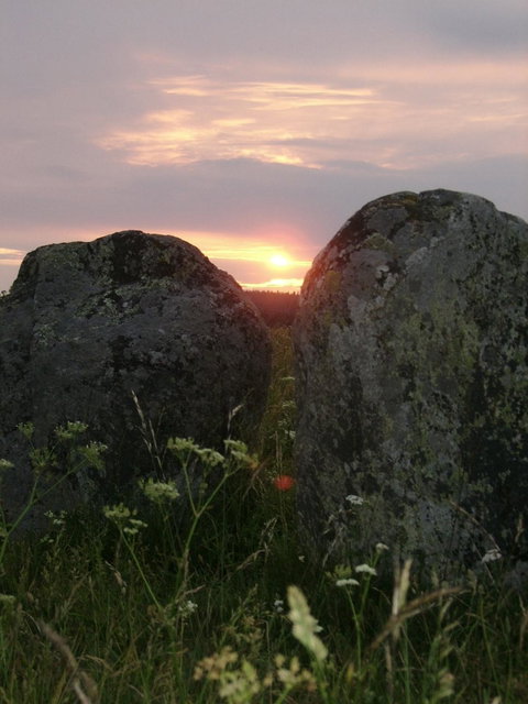 Två resta stenar uppe på Lunds backe med solnedgång som skymtar emellan dem
