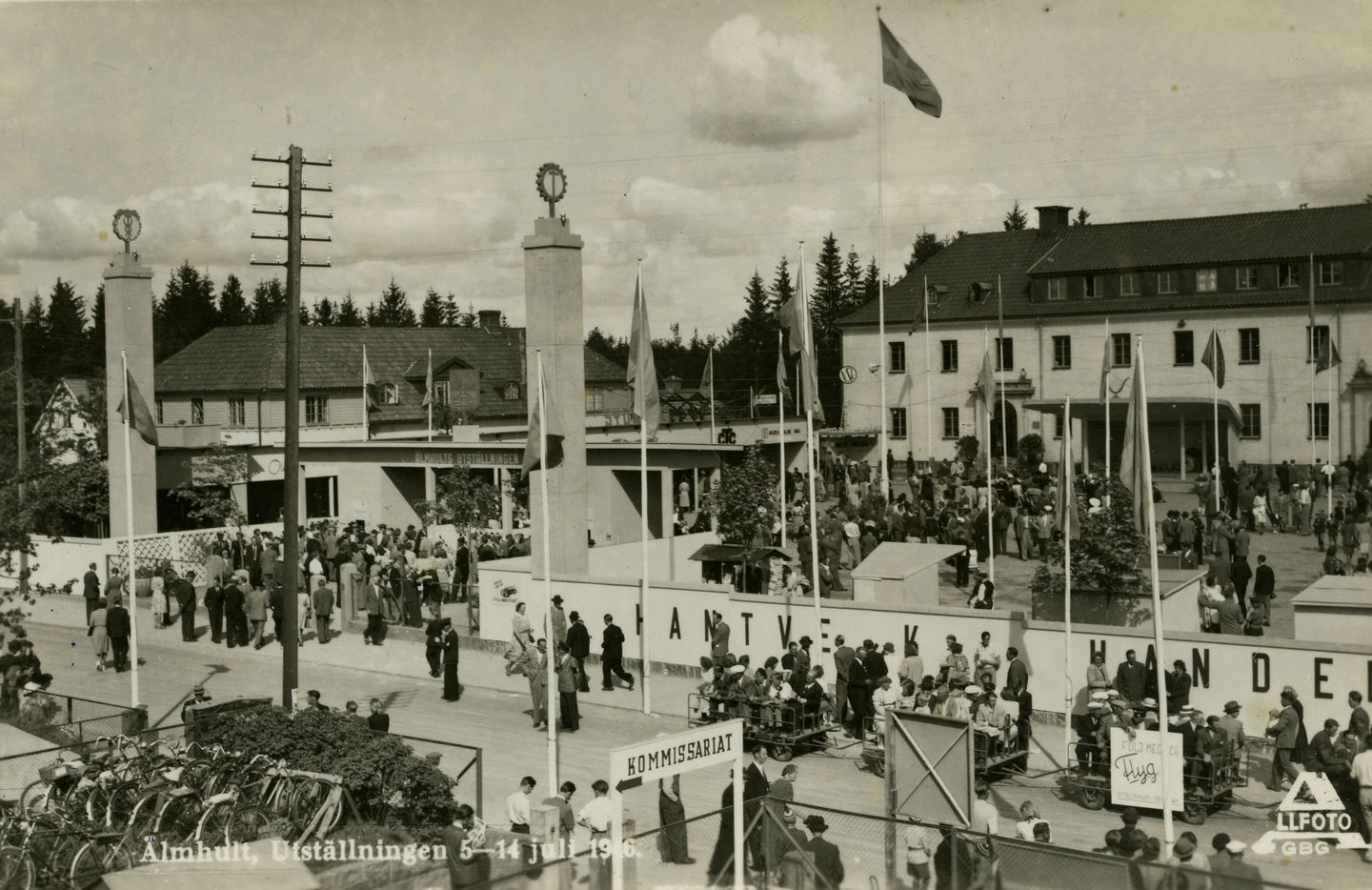 Kö av människor, flaggor och två rejäla pelare vid entrén. I bakgrunden syns Gemöskolan.