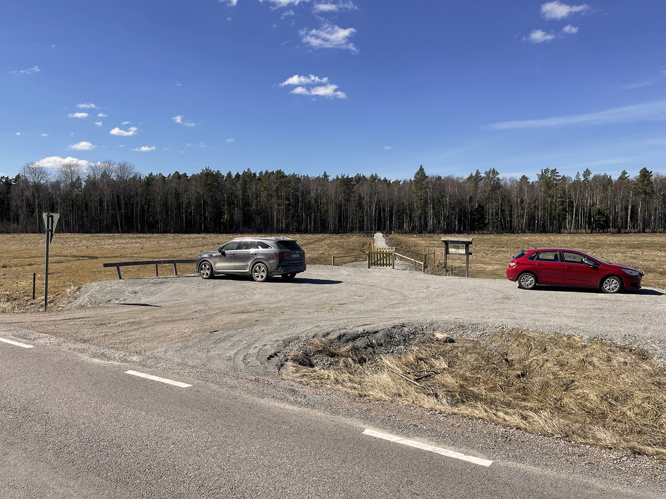 Grusad parkering. En röd och en grå bil står parkerade.