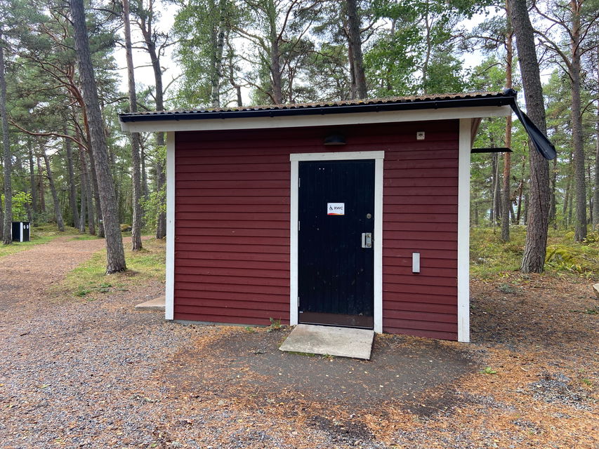 Ett litet rött hus med en svart dörr.