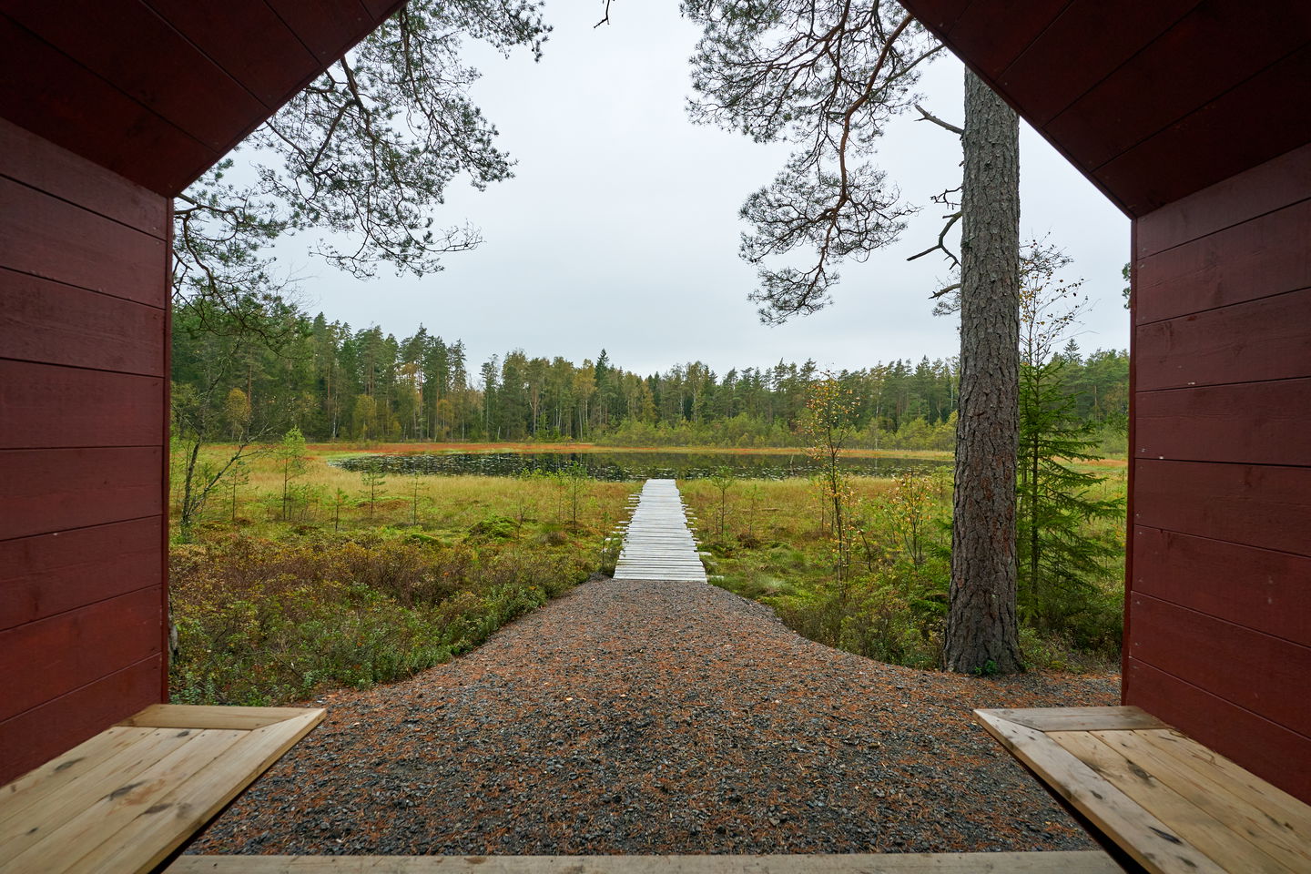 Vy från ett vindskydd ut mot en sjö med brygga
