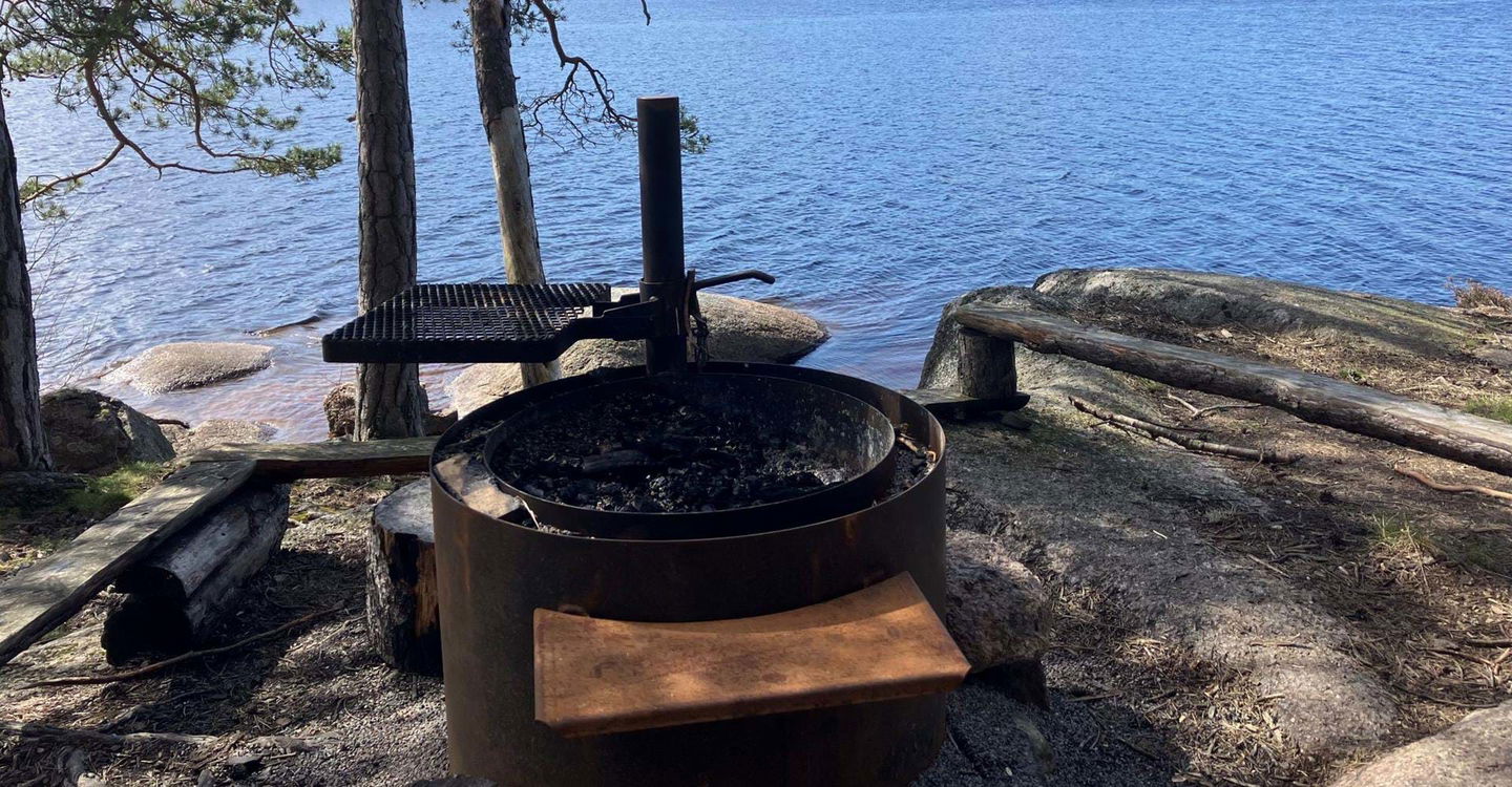 Corténgrill med höj- och sänkbart grillgaller. Bänkar runt om vid Ågelsjön, Norrviken.