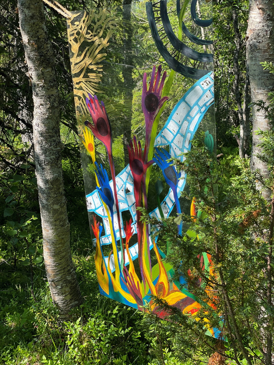 Ett konstverk på en glasskiva upphängd i skogen
