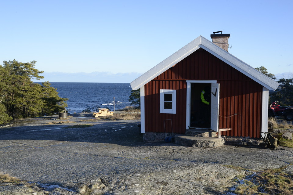 Röd stuga med utsikt mot havet