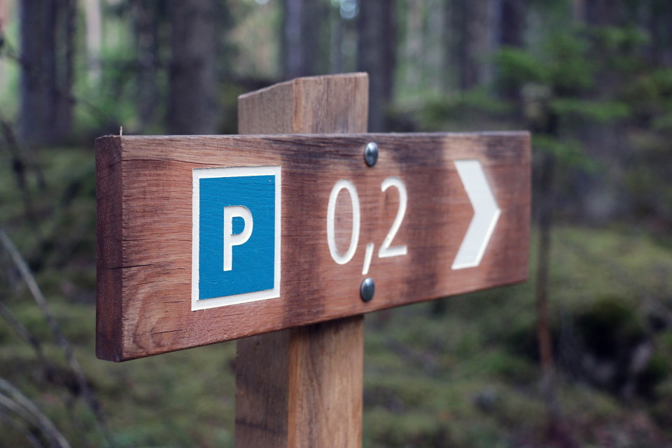 Skylt längs led som visar riktning och avstånd till parkering.