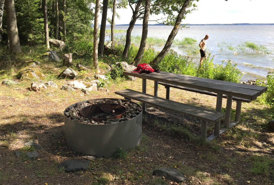 Eldstad och bänkar med bord nära vattnet.