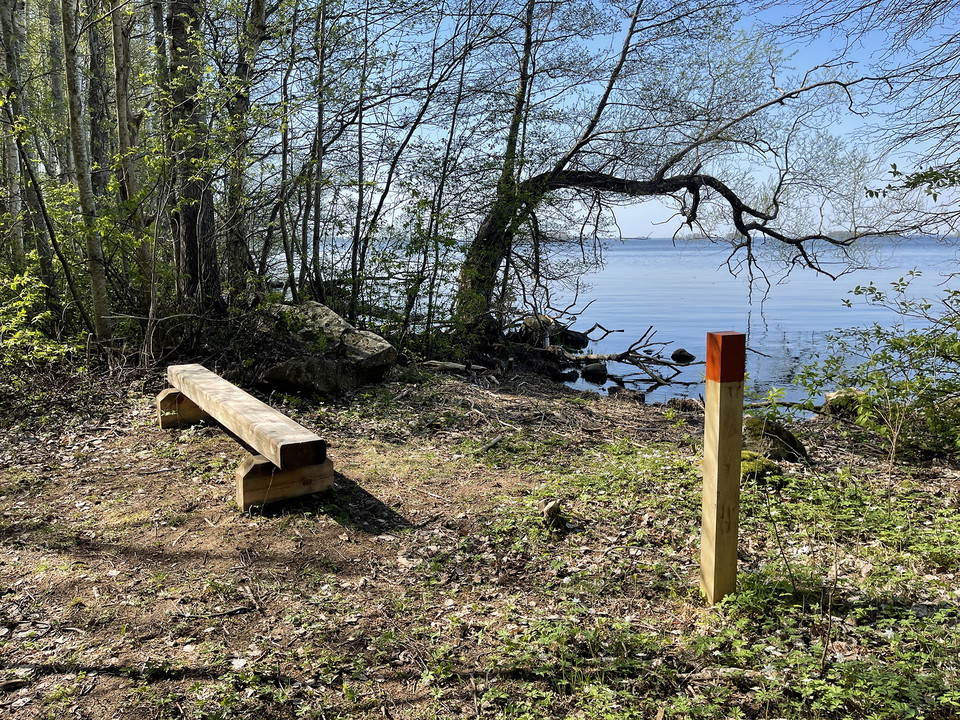 Stigmarkering vid en bänk med utsikt över sjö.