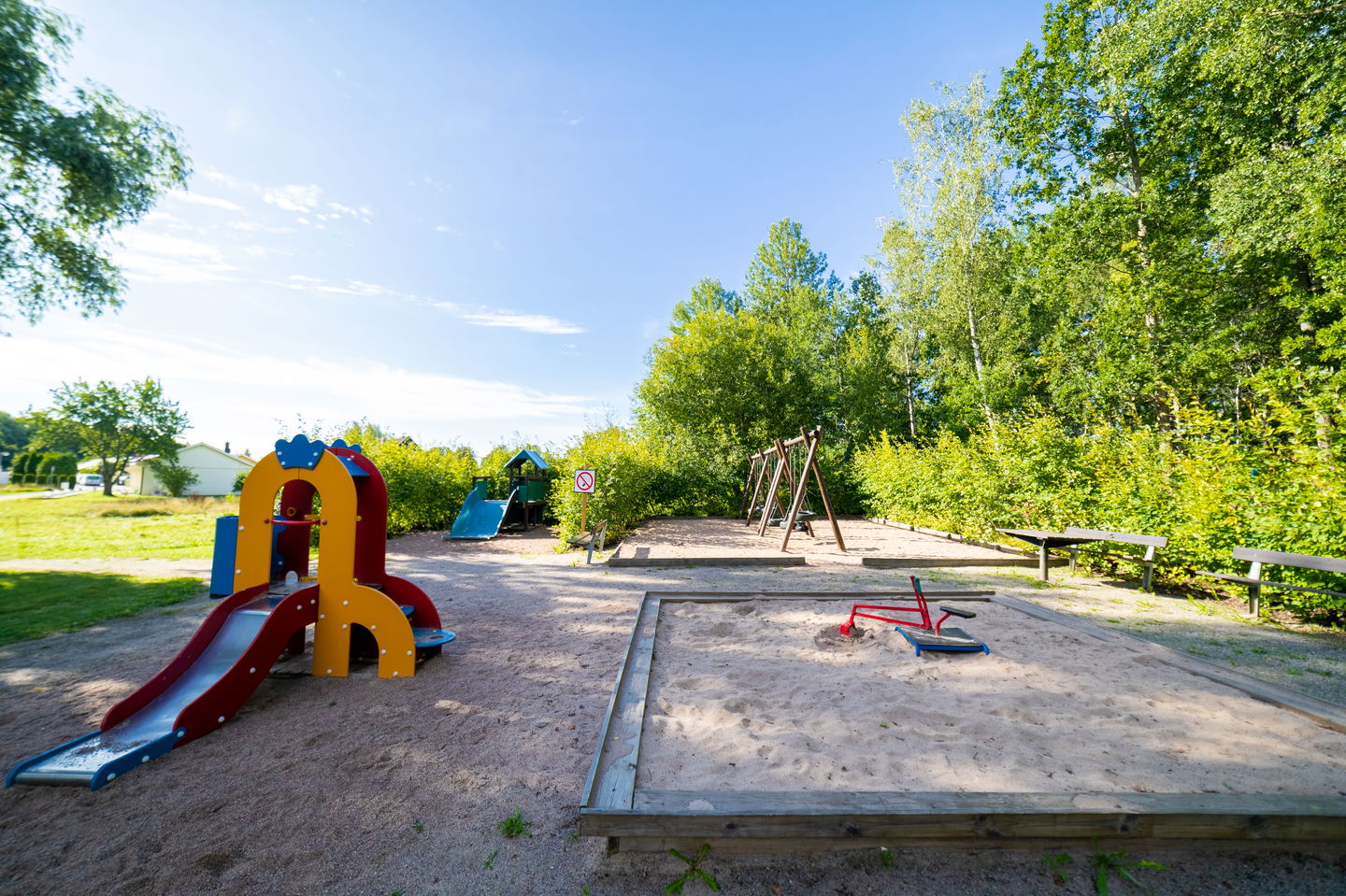 Lekparken i sin helhet med rutchkana, gungor, sandlåda och en större rutchkana