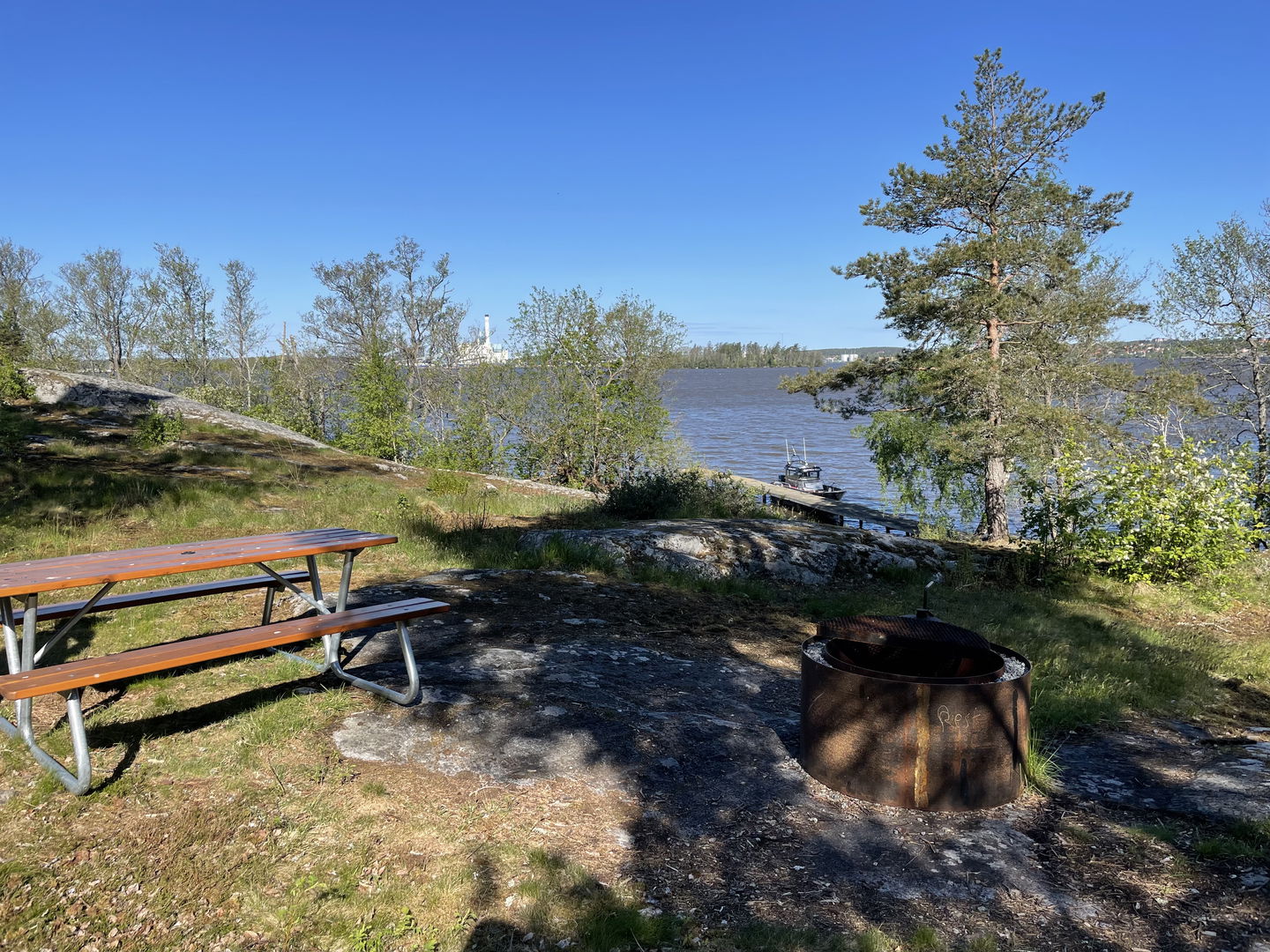 Bild på bord med bänkar och eldstad med utsikt över Mälaren.