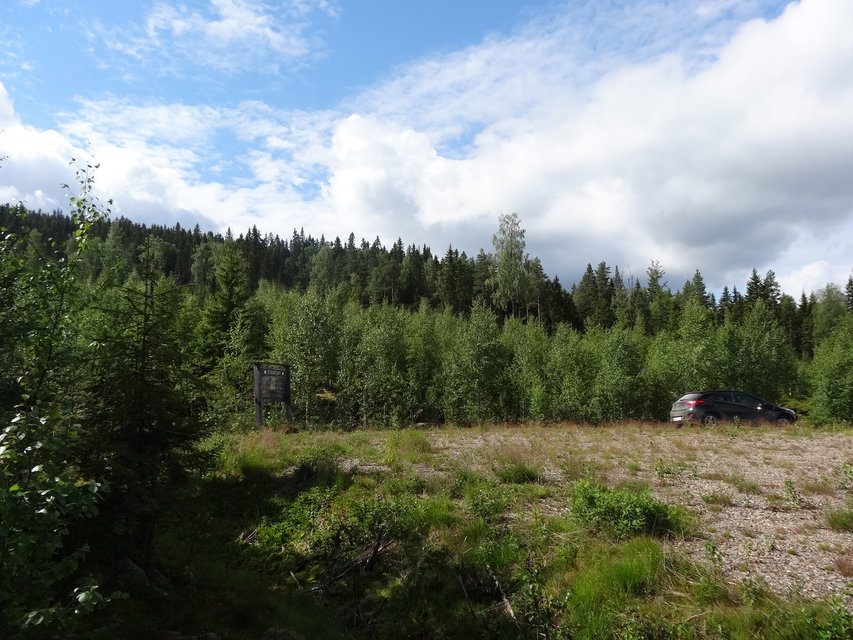 Grusparkering vid vändplan med skog runt om.