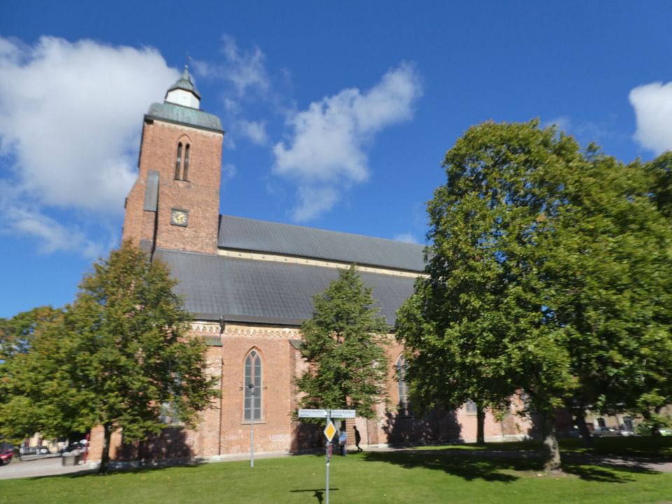 Kyrka i rött tegel, med högt torn. 