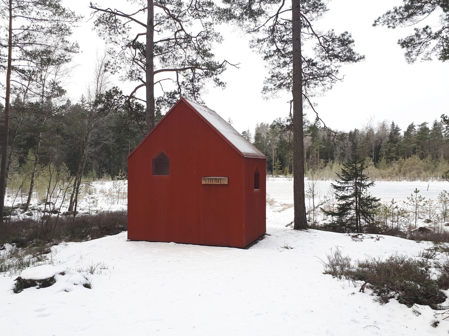 Vindskydd framför en sjö i vinterlandskap 