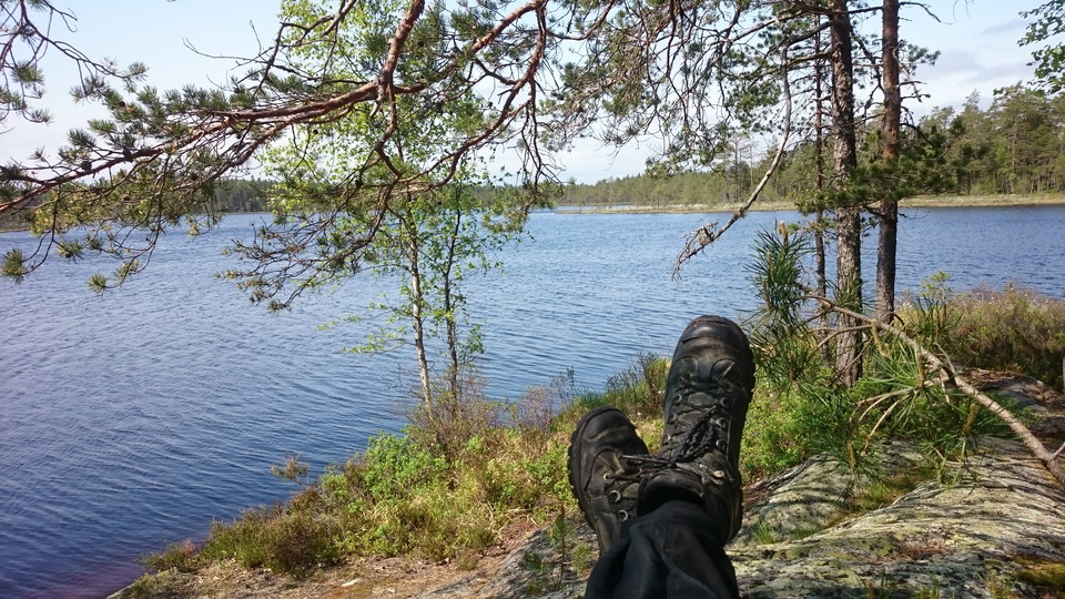 Två ben ligger korsade med föttena i luften med tjärnen i bakgrunden.