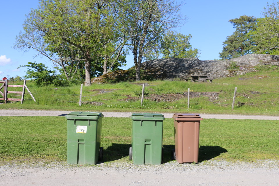 Två stora gröna soptunnor och en brun tunna för sortering av sopor.