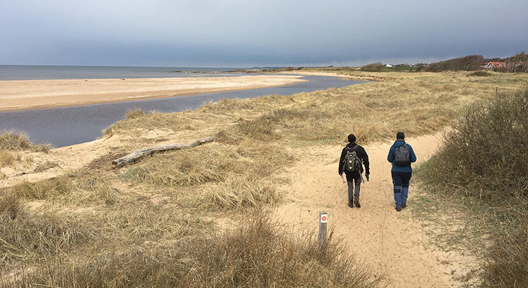 Två personer promenerar på en röd led vid havet