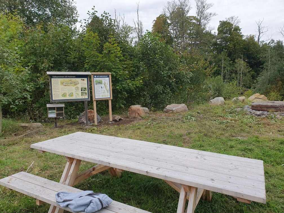 Informationstavlor med text och illustrationer över området. En picknickbänk.