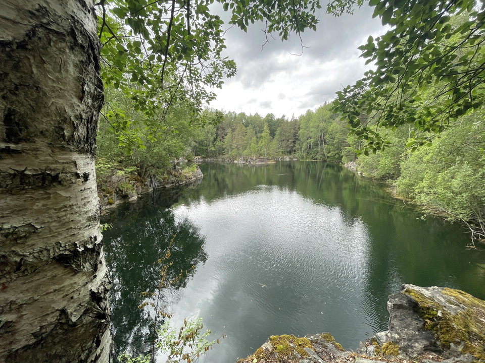 Vattenfyllt stenbrott kantad av skog.