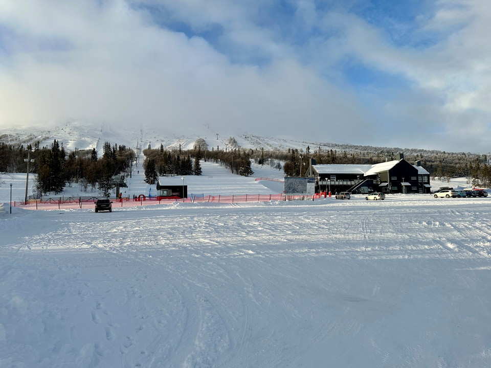 En stor tom parkeringsyta med ett brunt hus i och fjäll i bakgrunden