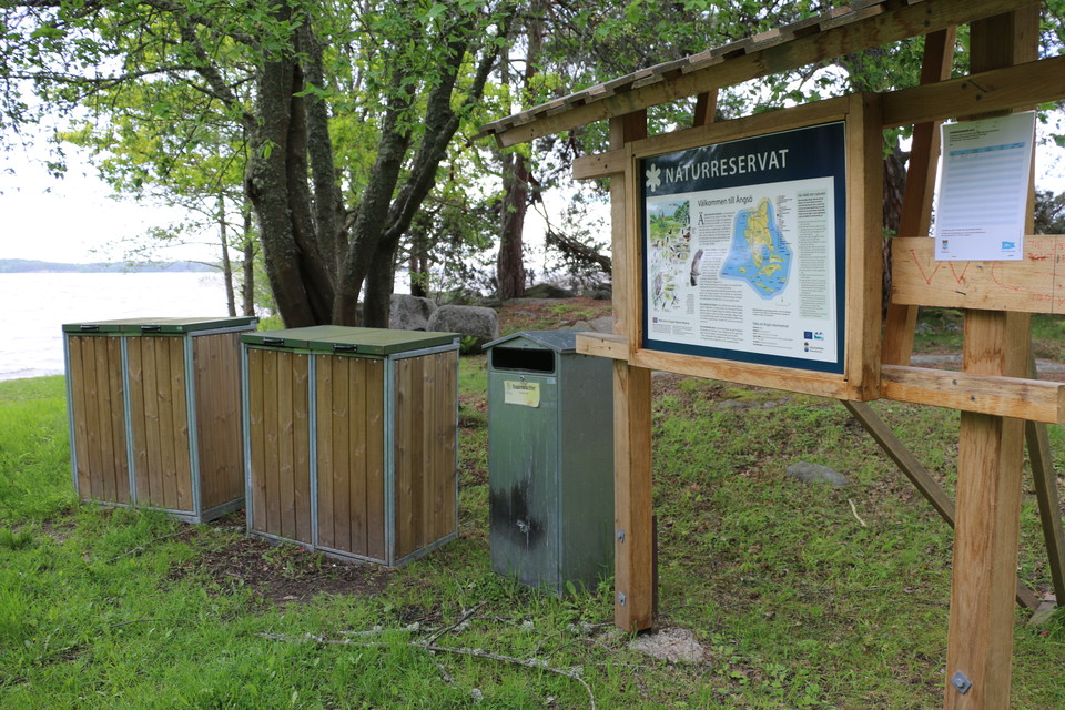 Informationstavla och soptunnor.