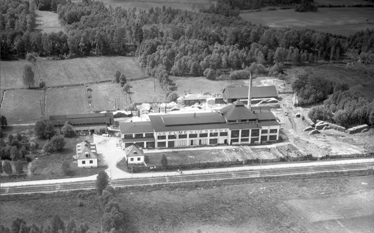 En långsmal fabriksbyggnad intill ett järnvägsspår. 