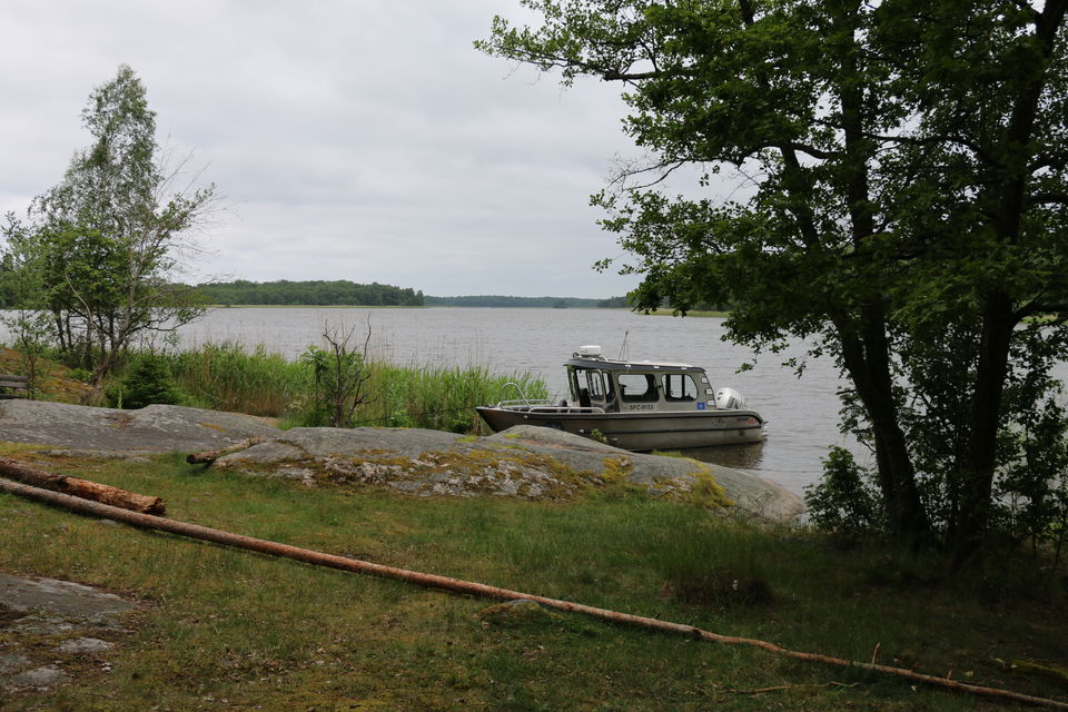 En båt ligger förtöjd intill en klippa.