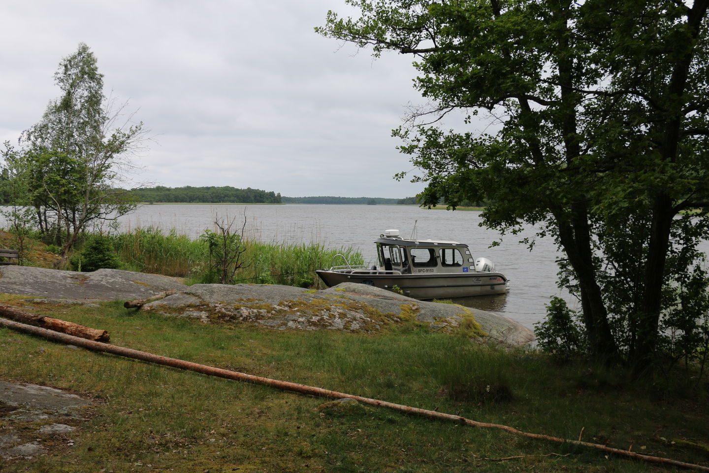 En båt ligger förtöjd intill en klippa.