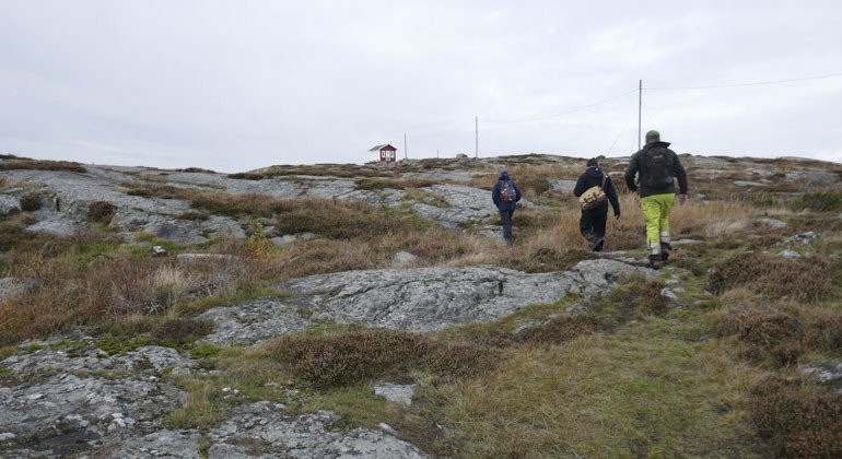 tre personer som går över stenig mark