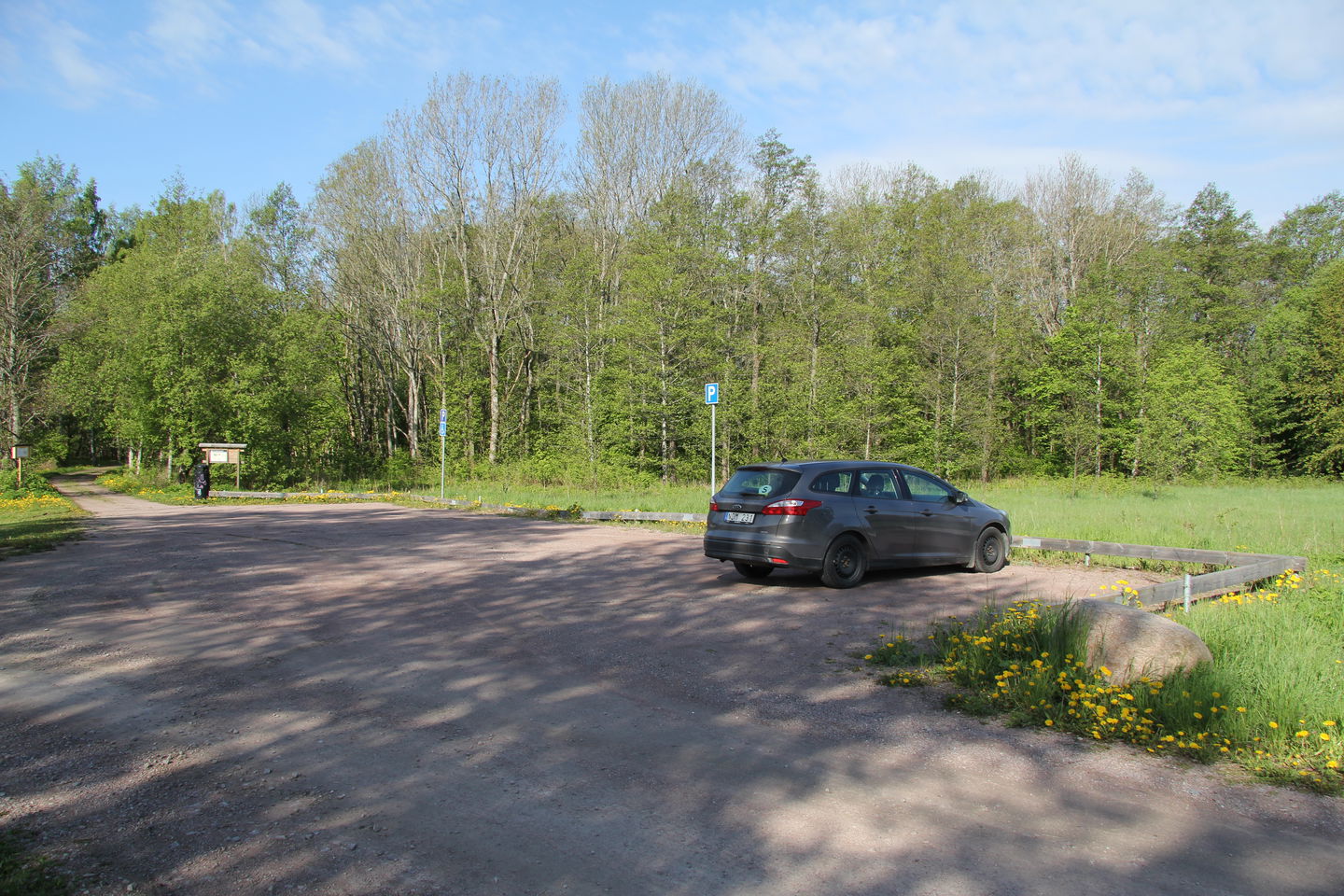 Bil parkerad på parkering. I bakgrunden syns informationstavlan.