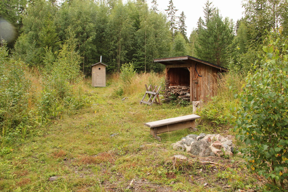 Litet gråmålat utedass, Vedskjul och eldstad