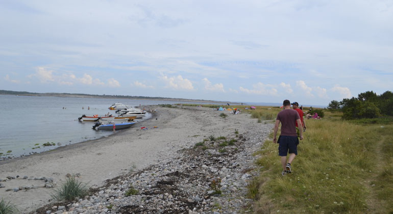 två personer som går längst med strandkanten