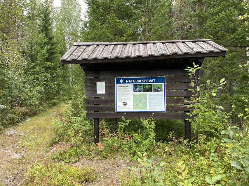 En informationsskylt på ett skyltställ vid en stig.