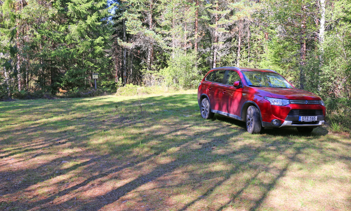 Bil parkerad i förgrunden. I bakgrunden skymtas en informationstavla.