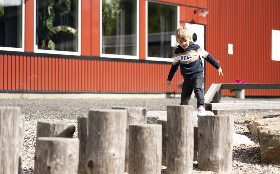 Ett barn balanserar på stockar i en hinderbana